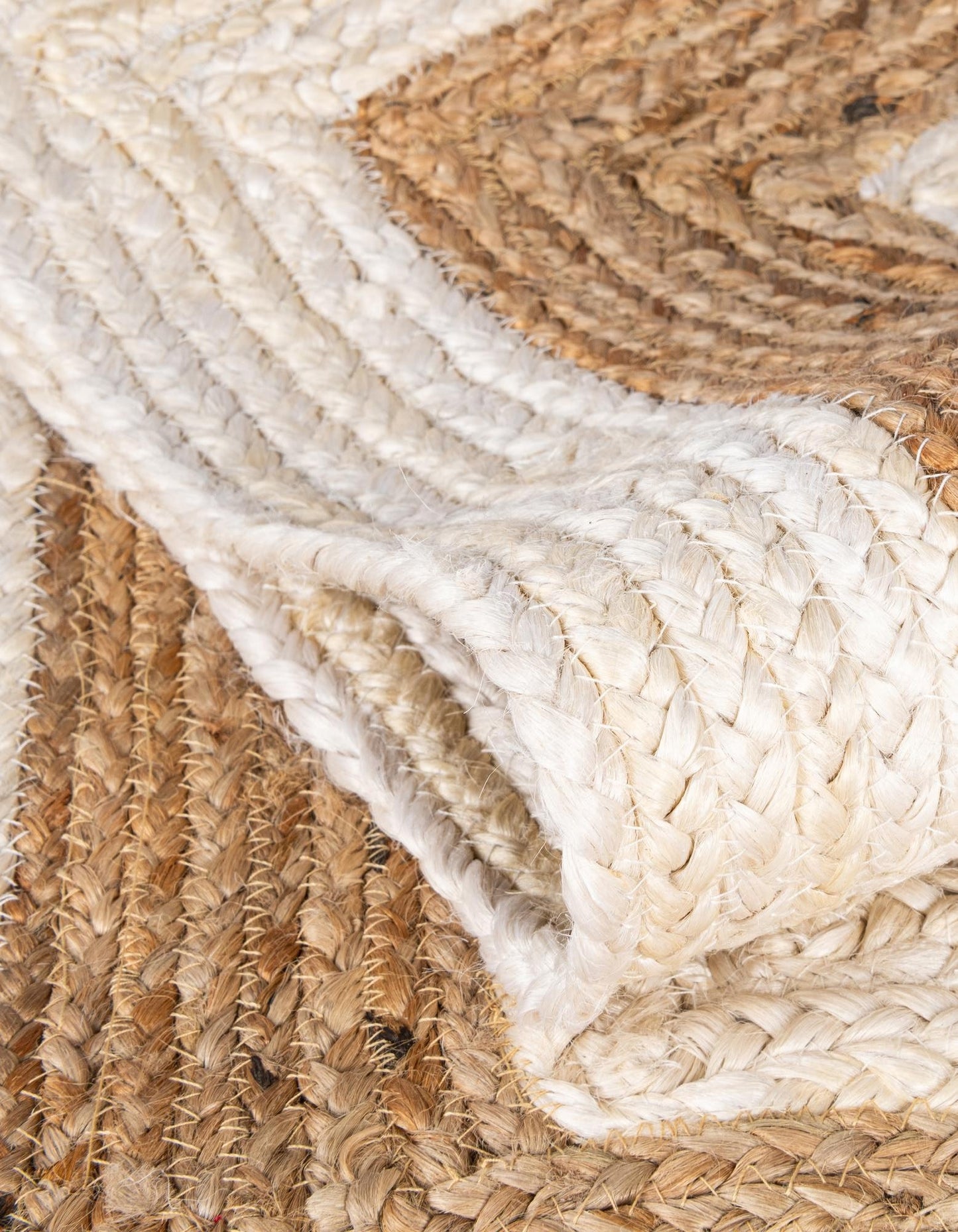 Close-up of a woven jute rug with natural brown and white colors.