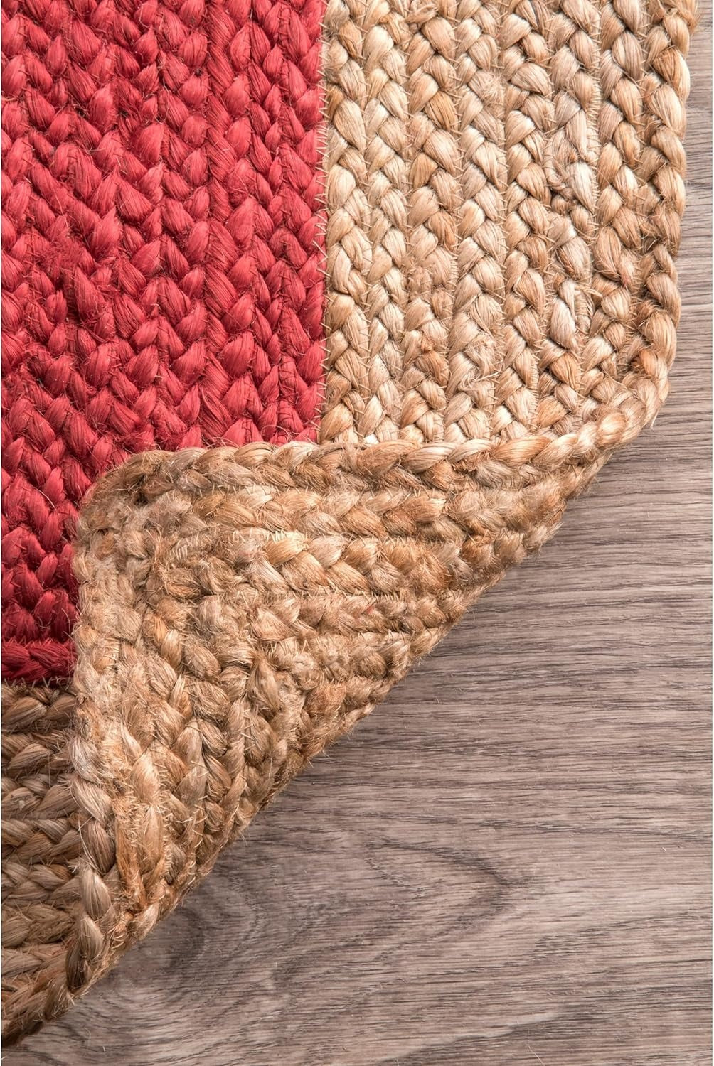 Close-up of a red and beige braided rug on a wooden floor.