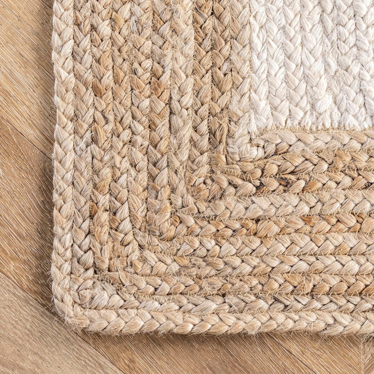 Close-up of a braided natural fiber rug on a wooden floor.