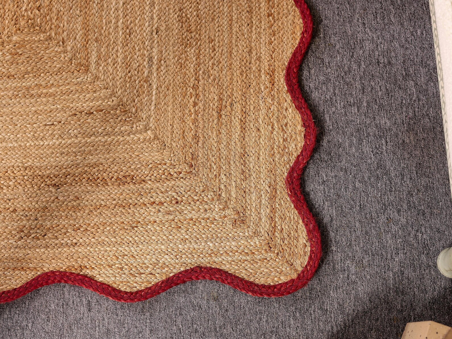 Close-up of a textured rug with a red border on a gray surface