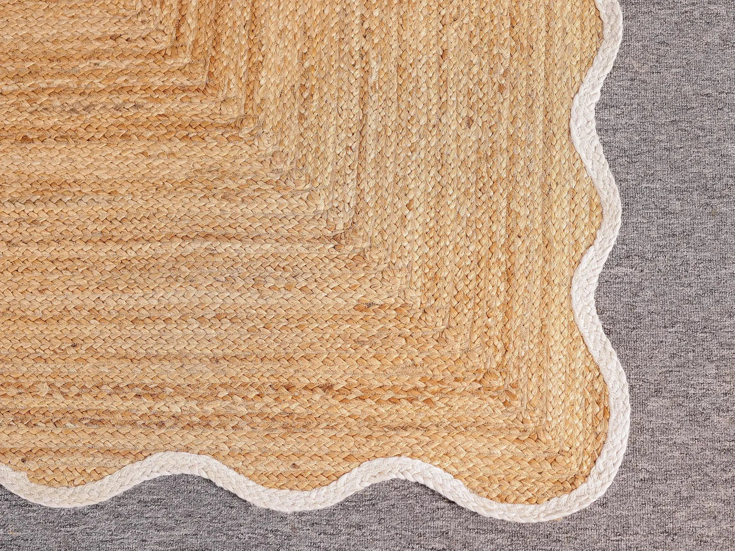 Close-up of a textured beige rug corner on a gray background