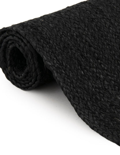 Folded black jute rug showing thickness flexible handmade woven carpet