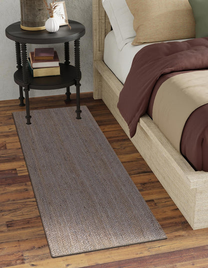 Bedroom with a bed, side table, and rug on wooden flooring.