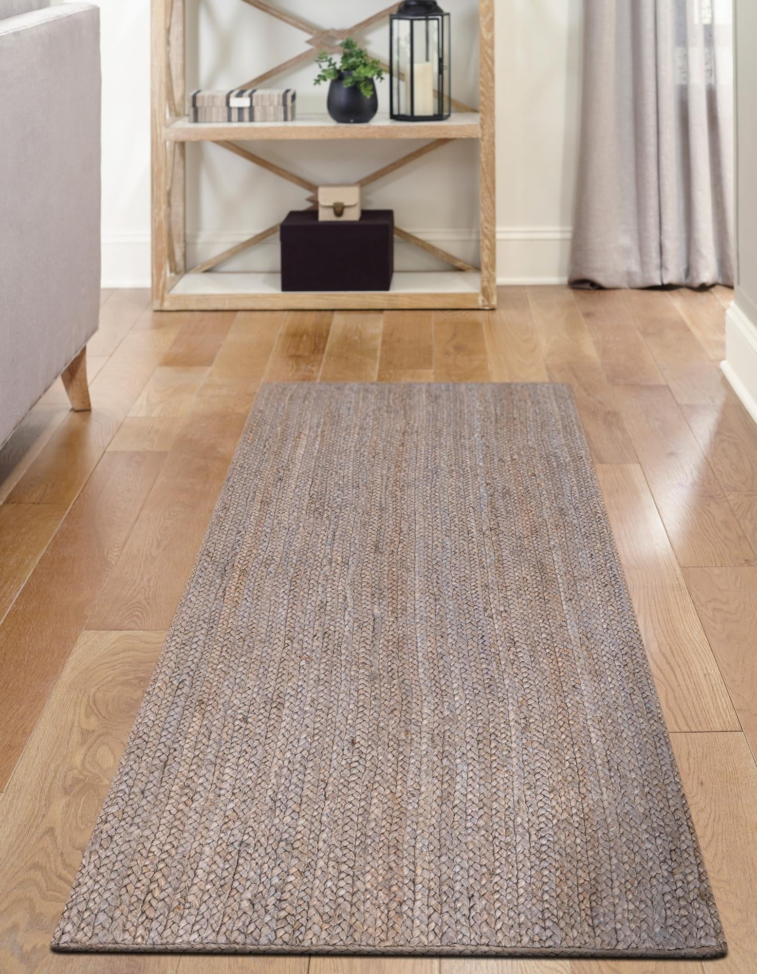 Gray runner rug on a wooden floor with a shelf in the background