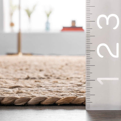 Beige woven rug on a light wooden floor with a ruler for scale.