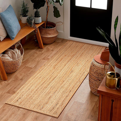 Beige jute rug on a wooden floor with decorative elements like a bench, baskets, and plants.