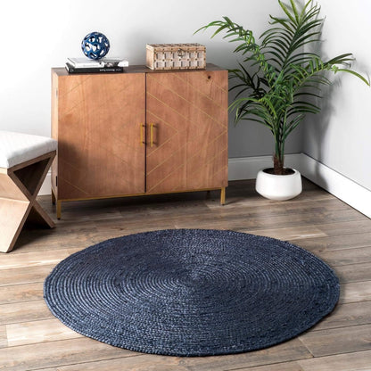 Round blue rug on a wooden floor with a wooden cabinet and plant in the background.