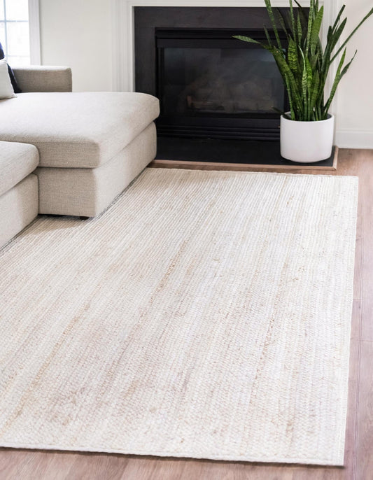 Living room with a beige rug, white sofa, and a plant in front of a fireplace.