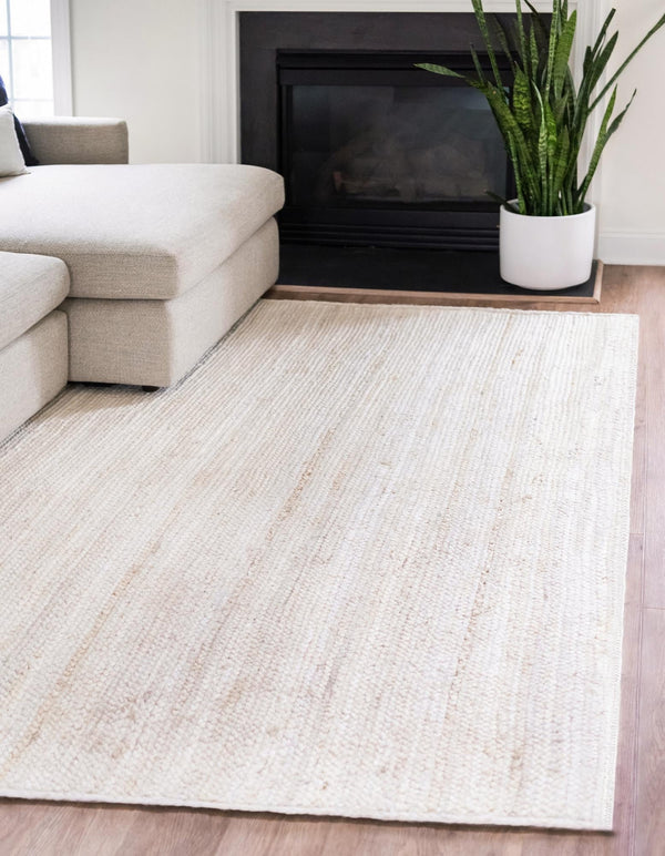 Living room with a beige rug, white sofa, and a plant in front of a fireplace.