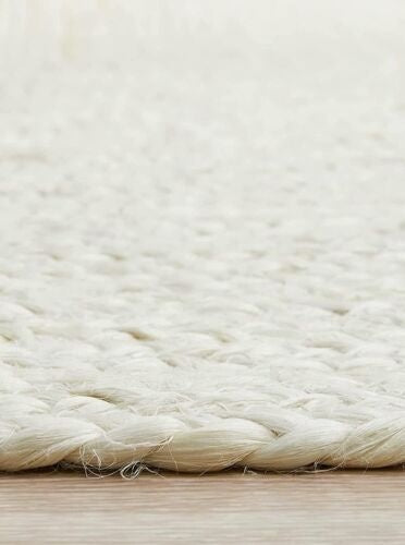 Close-up of a textured white rug on a wooden floor