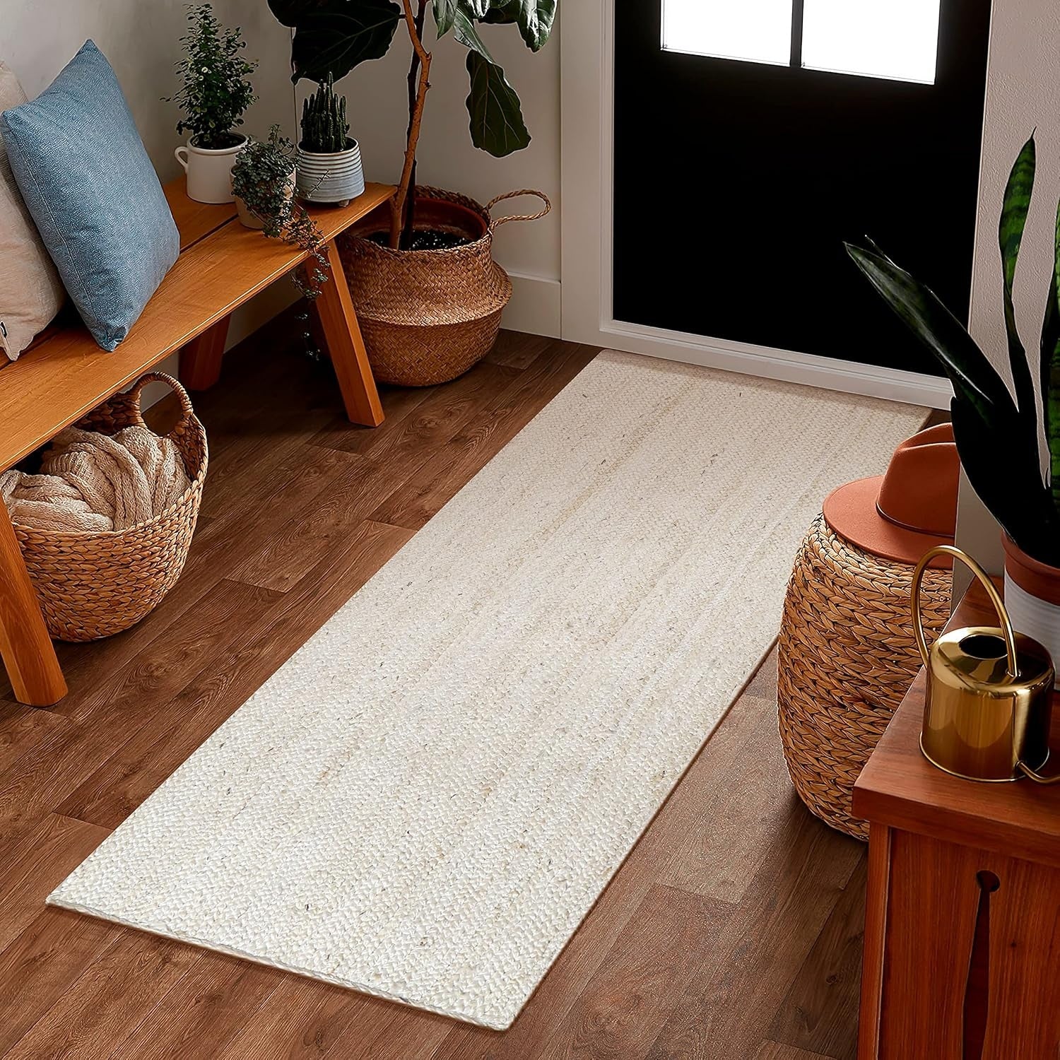 Entryway with a white woven rug, wooden bench, and potted plants.