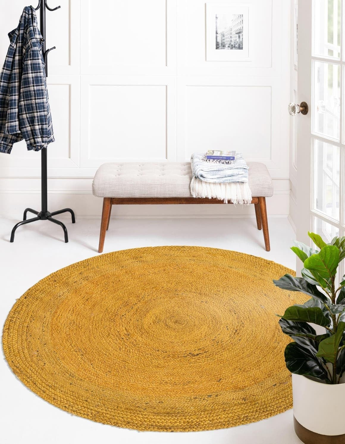 Round yellow rug in a room with a bench, coat rack, and plant.