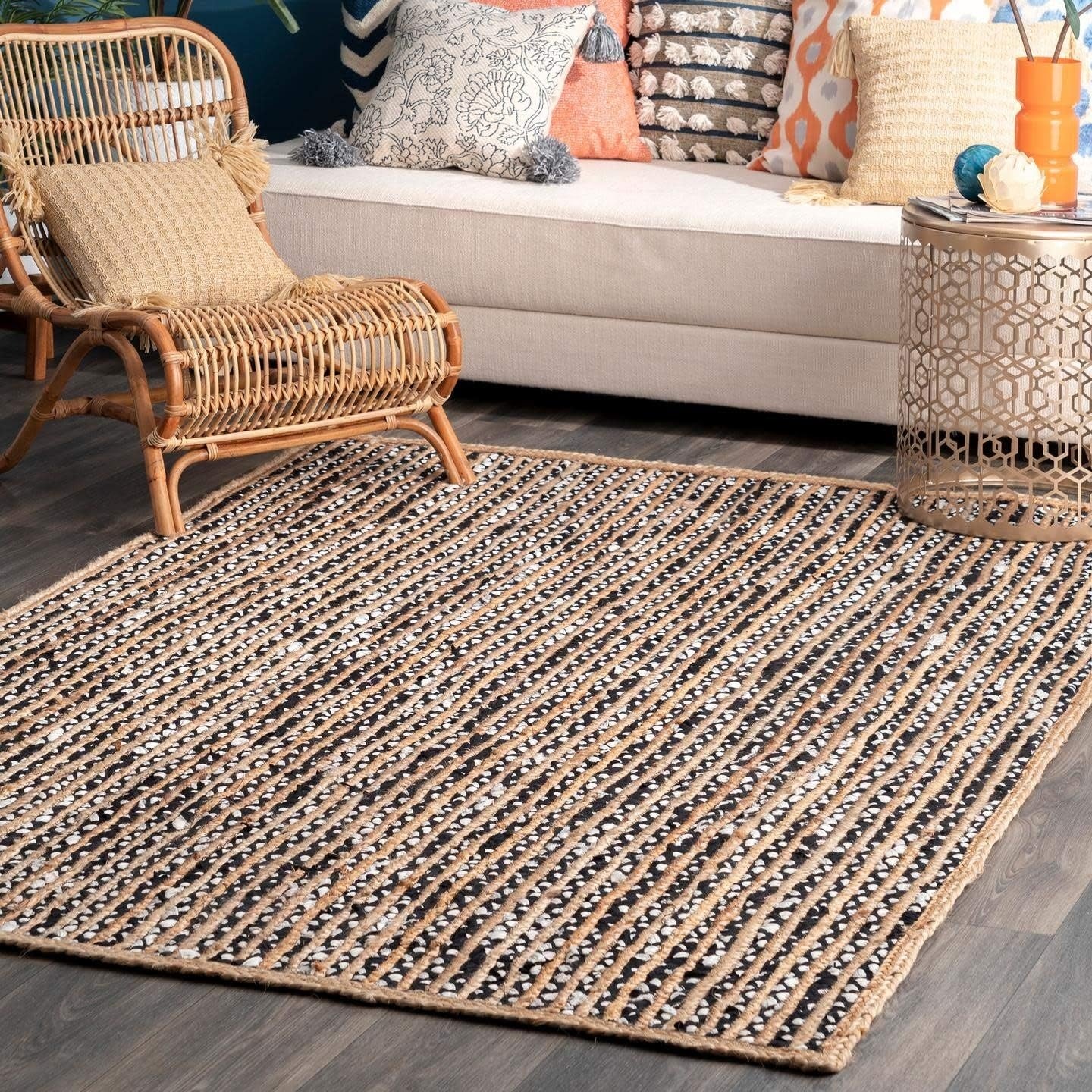 Living room with a woven rug, wicker chair, and colorful cushions on a sofa.