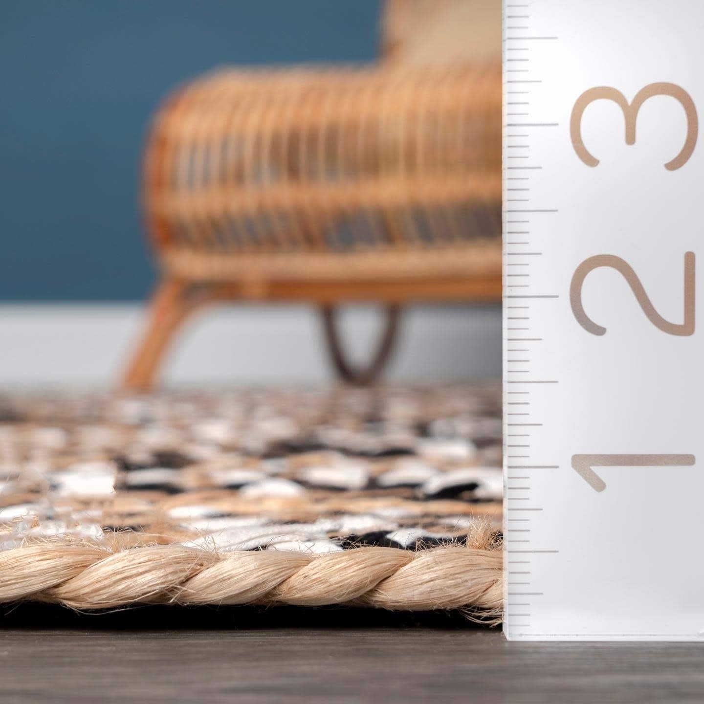 Rattan chair and rug with a ruler for scale against a blue wall.