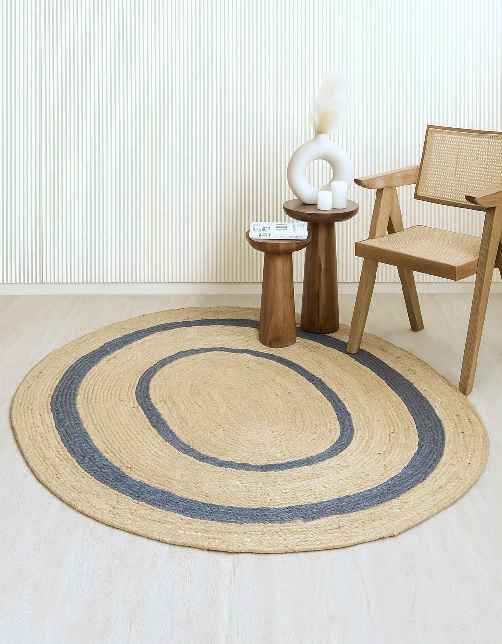 Oval jute rug with blue accents in a room with a wooden chair and side table.