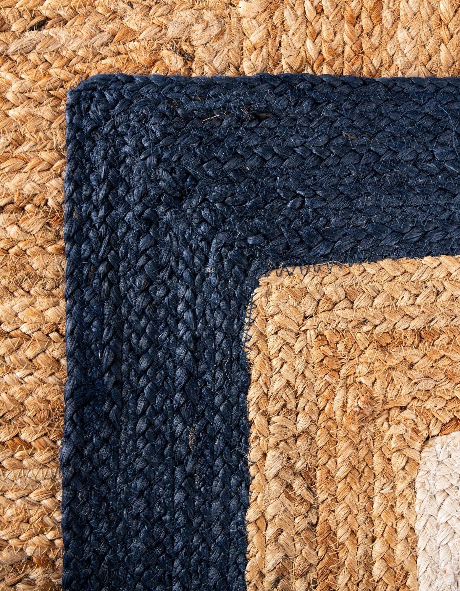 Close-up of a woven rug with a dark blue border and natural fiber texture.