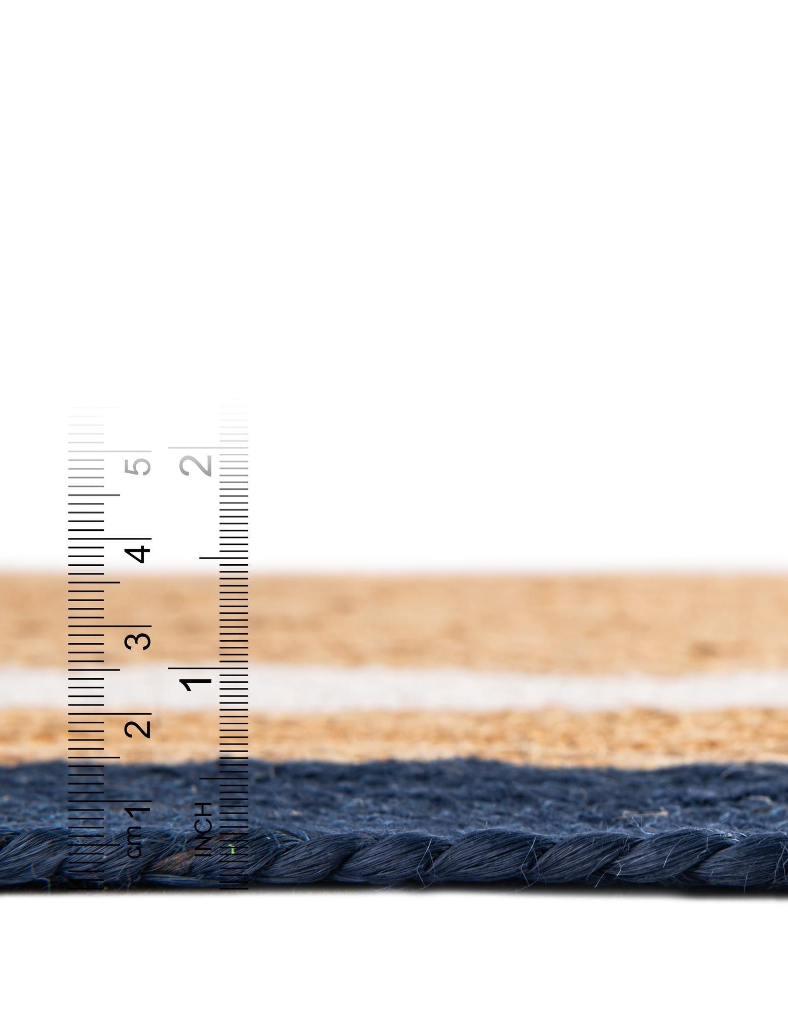 Close-up of a woven mat with a ruler for scale on a white background