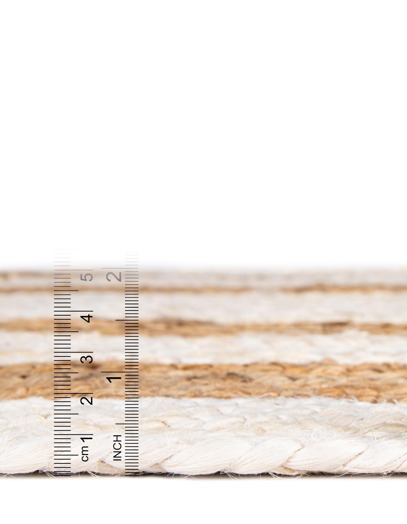 Close-up of braided rope with a ruler for scale on a white background
