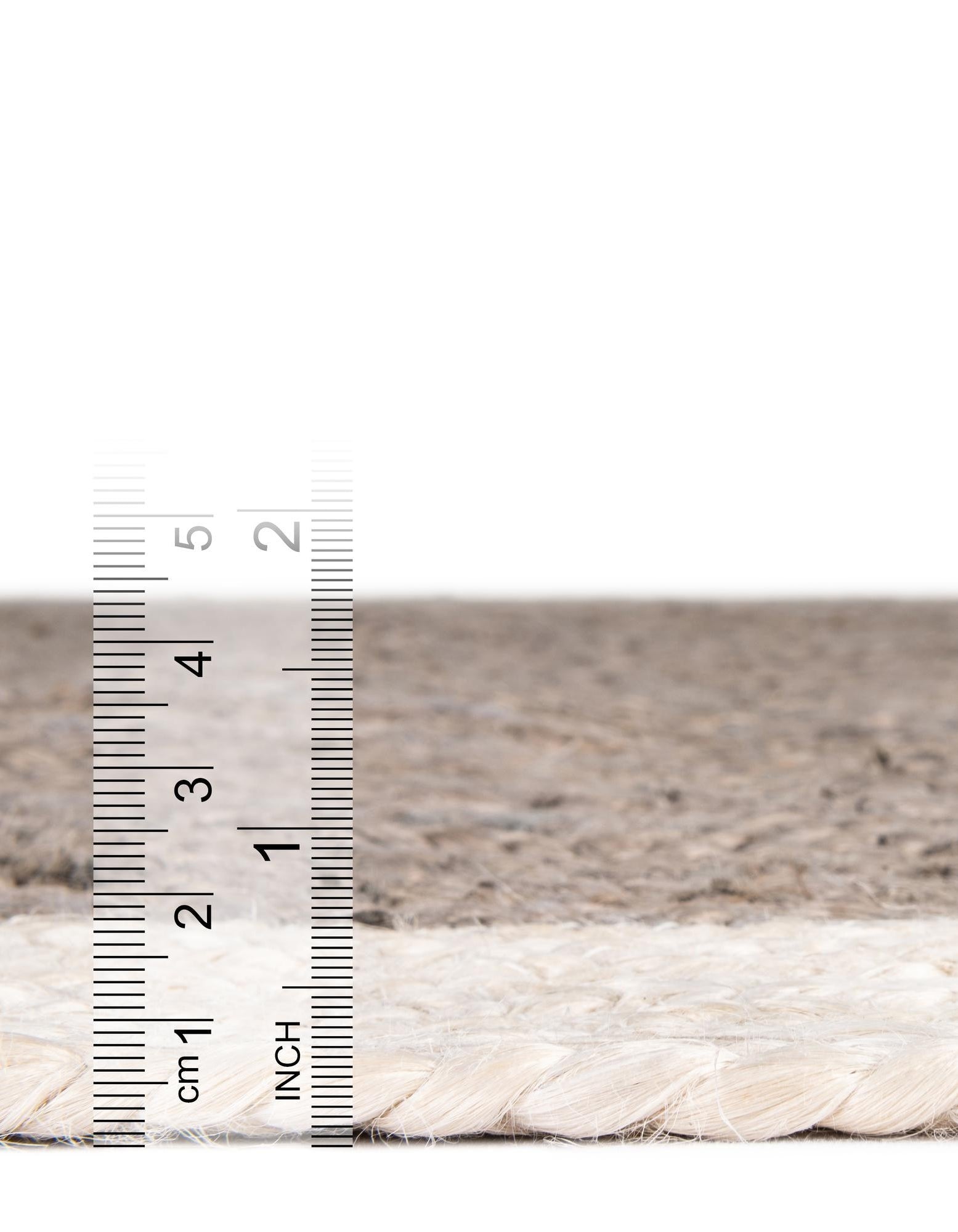 Close-up of a rope with a ruler for scale on a neutral background