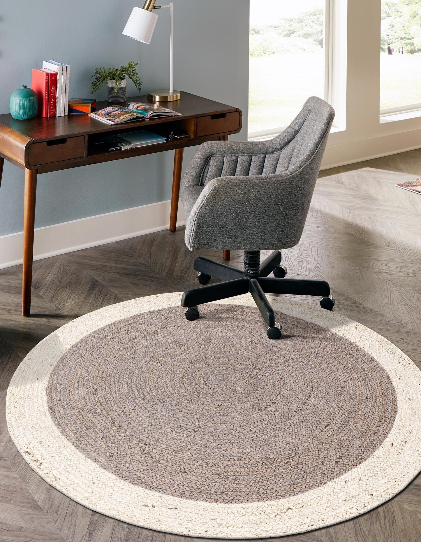 Home office with a desk, chair, and round rug on a wooden floor.