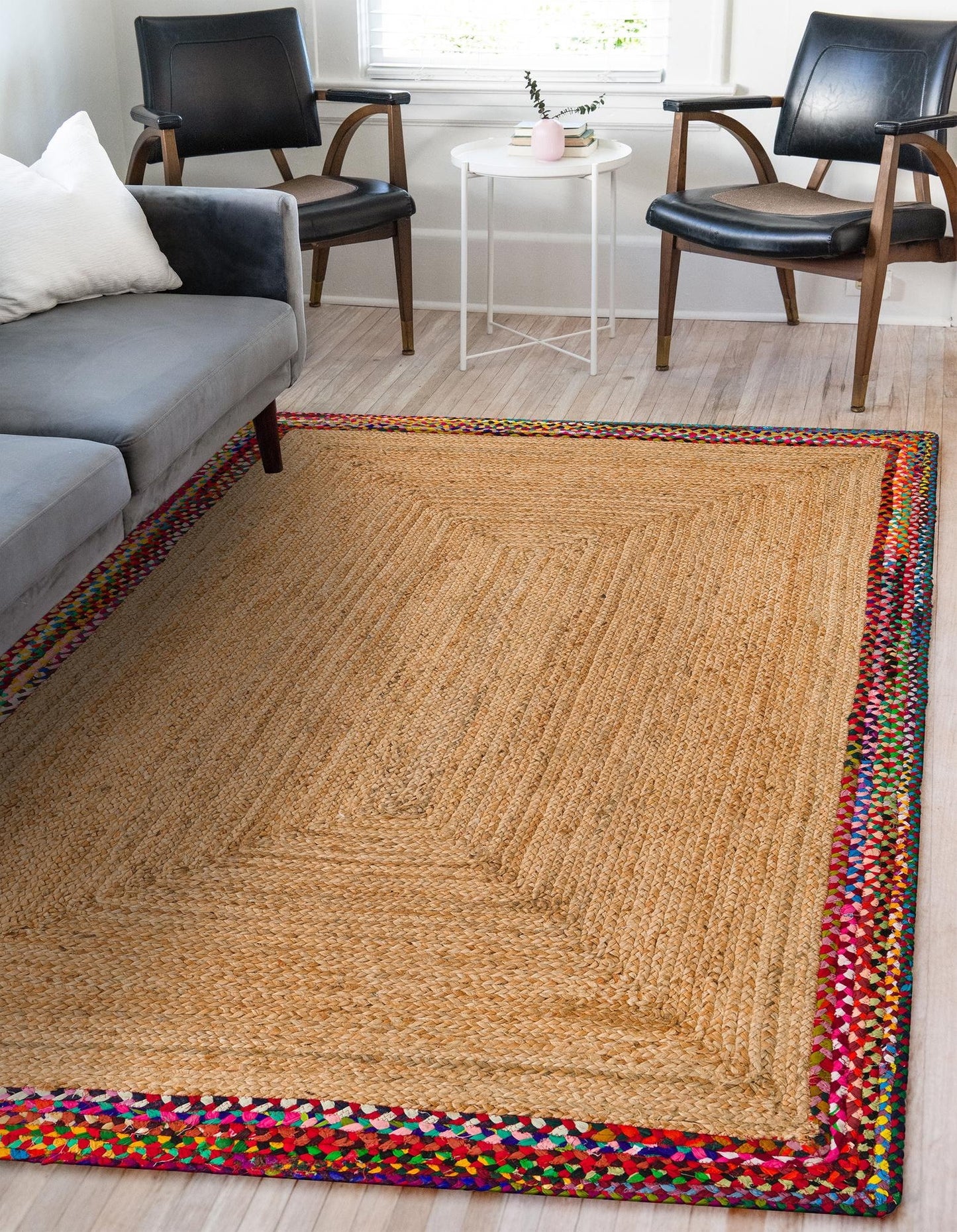 Living room with a braided rug, gray sofa, and black chairs.