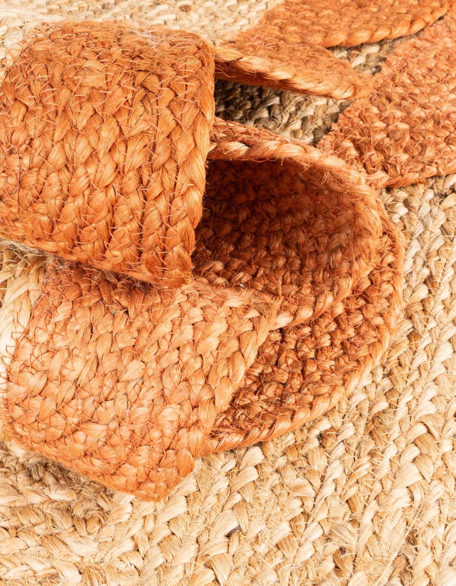 Close-up detail of natural jute rug with burnt orange scalloped edge, showing premium braided texture, thick weave, handcrafted stitching, and durable artisan finish