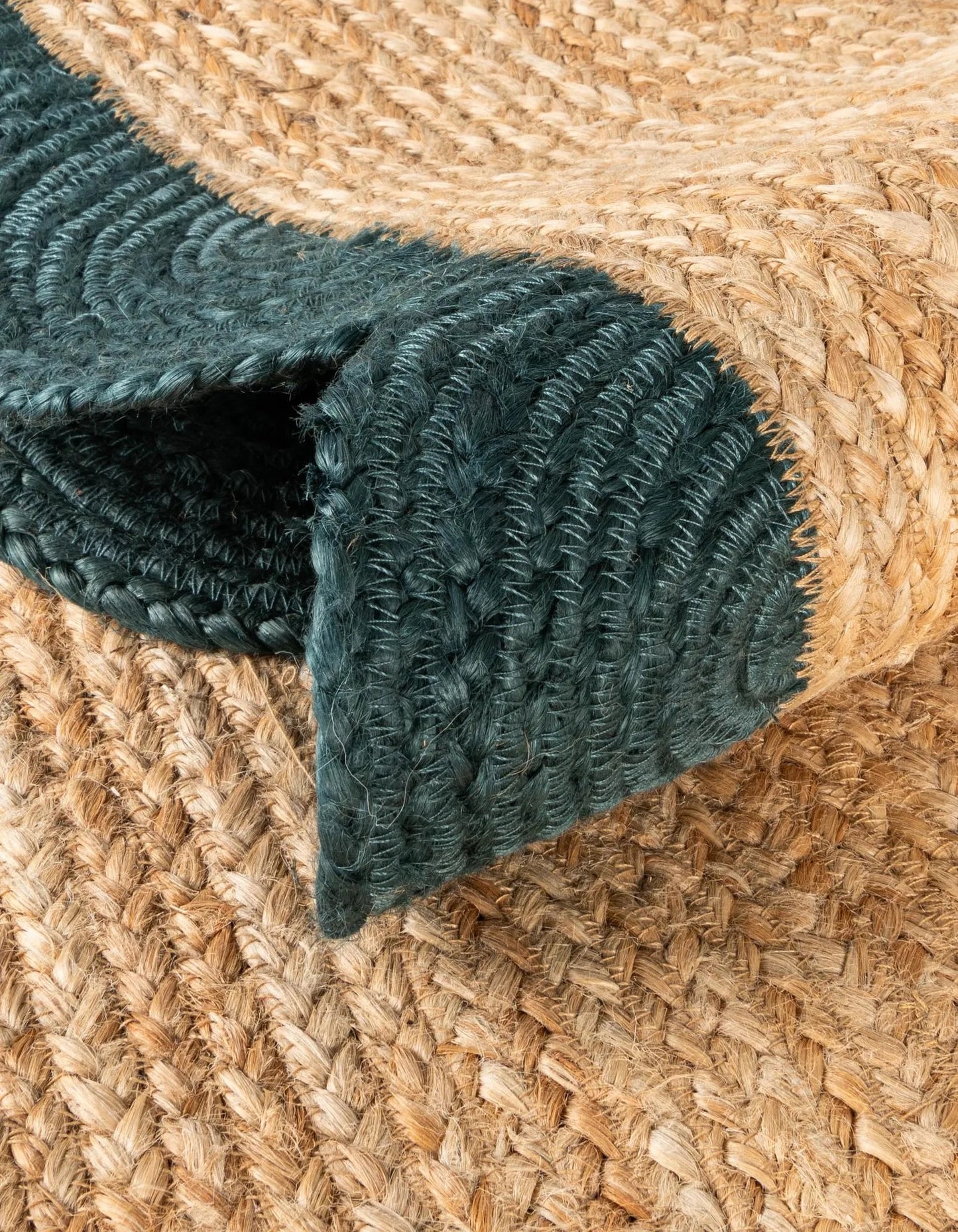 Close-up of a textured green rug corner on a woven beige surface