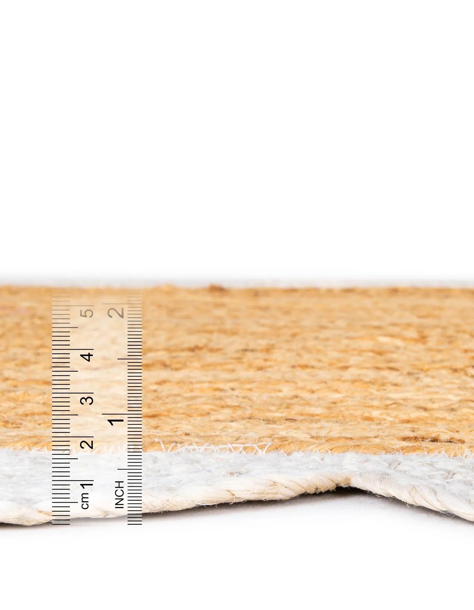 Side profile of handmade jute rug with white scalloped border, low pile flatweave design and sturdy natural fiber construction for long-lasting use