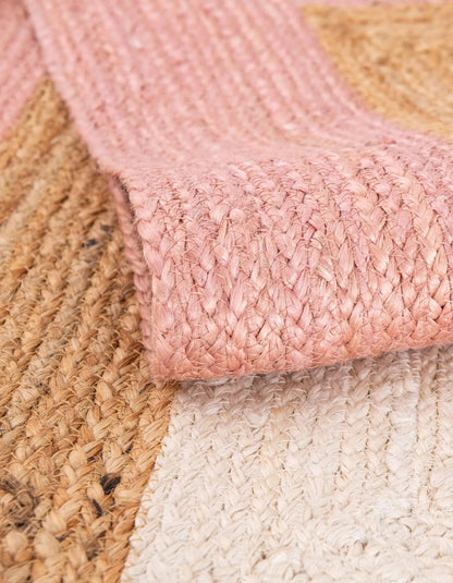 Close-up of pink braided rug with beige and white rugs underneath