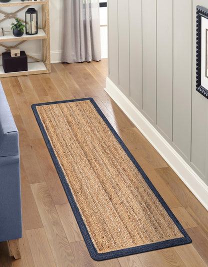 Long rectangular rug with a blue border on a wooden floor in a room.