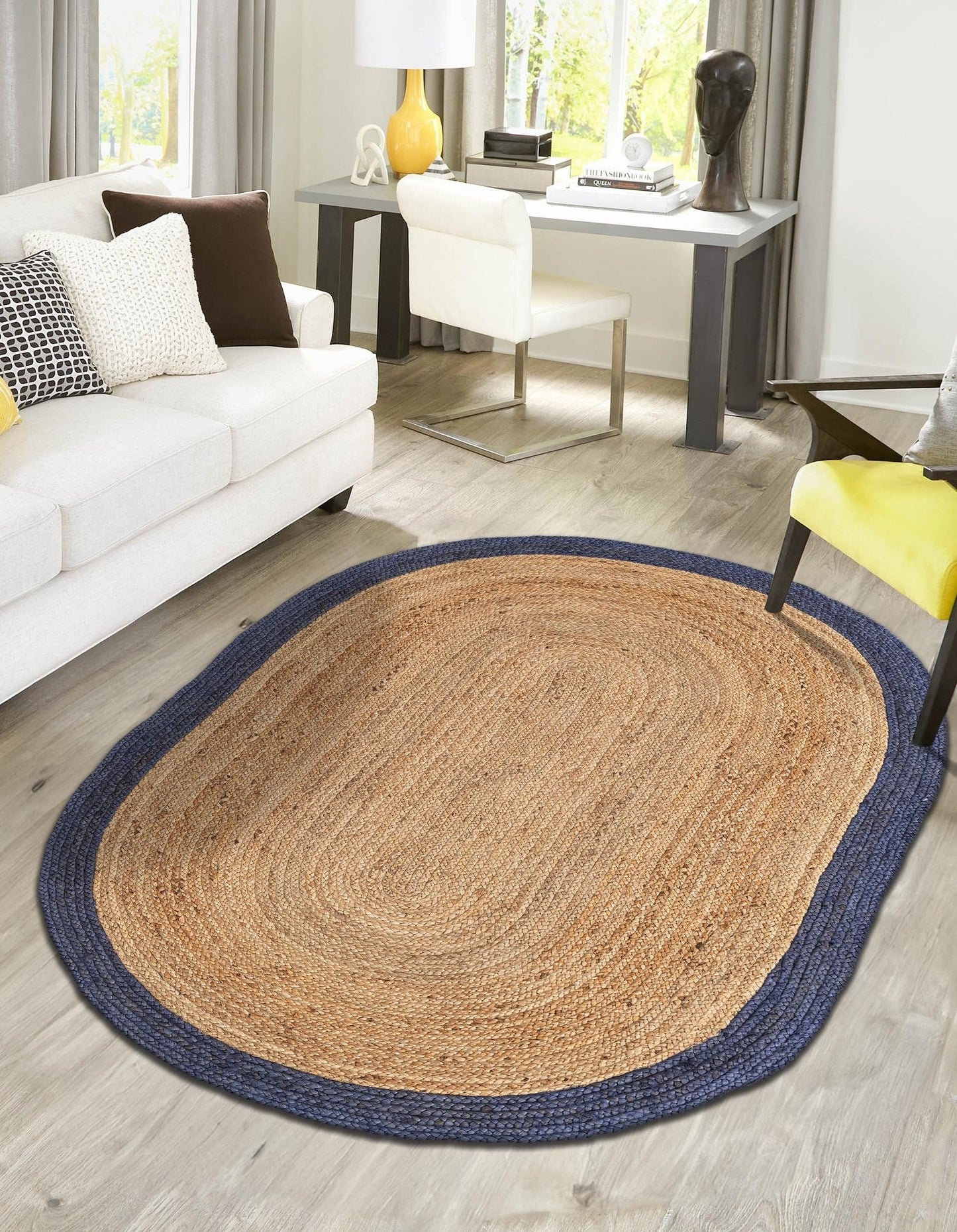 Oval jute rug with blue border on wooden floor in living room