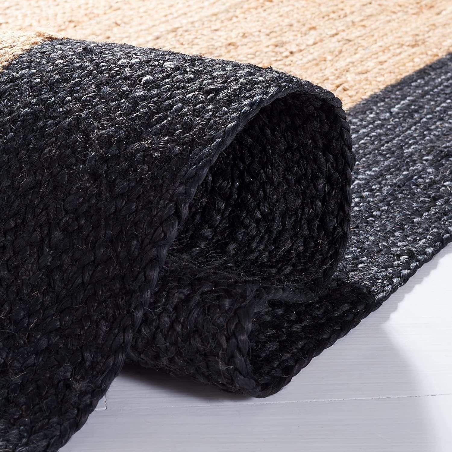 Roll of black textured carpet on a light wooden floor