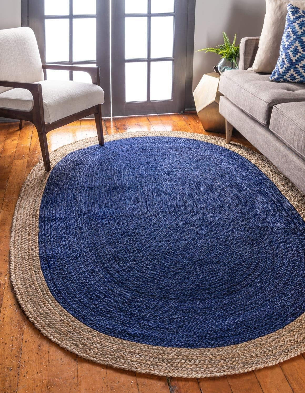 Round blue and beige braided rug in a living room setting with a sofa and chair.