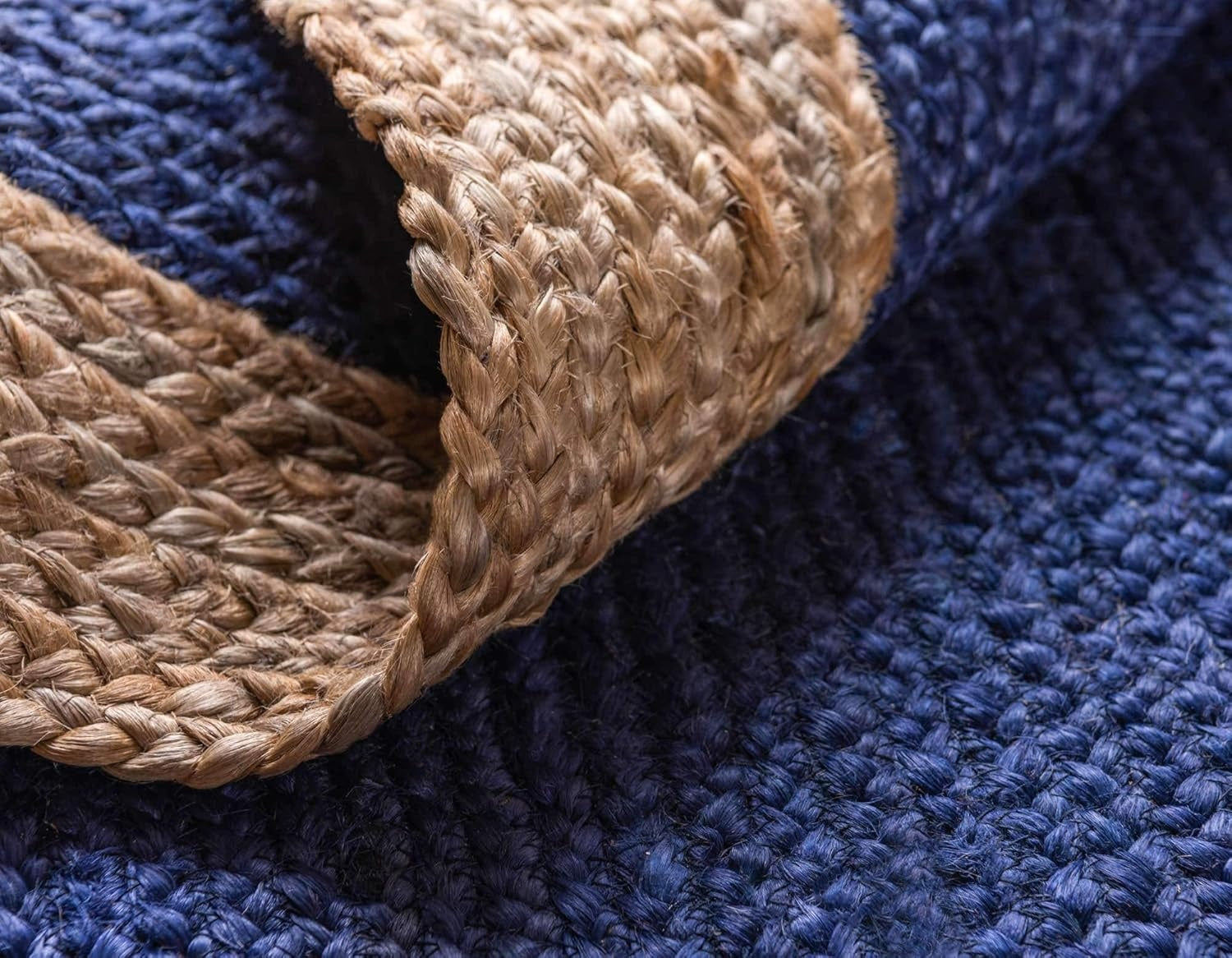 Close-up of a blue textured rug with a woven brown border.
