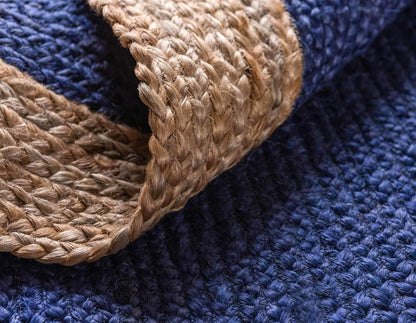 Close-up of a blue textured rug with a woven brown border.