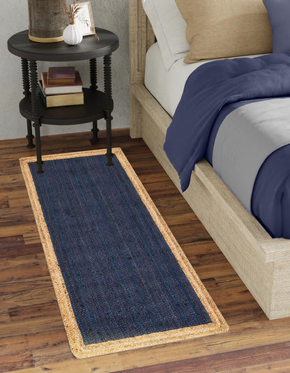 Navy blue runner rug on a wooden floor next to a bed with a side table.