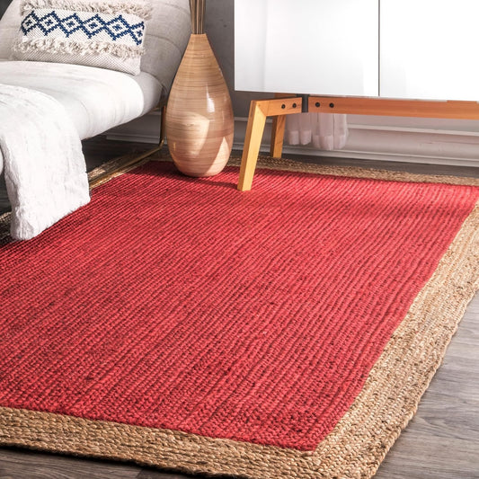 Red and beige braided rug in a living room setting with a wooden side table and decorative pillow.