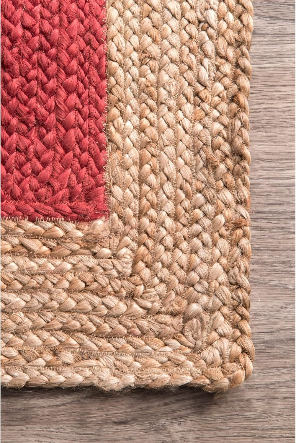 Close-up of a woven rug with red and beige patterns on a wooden floor.