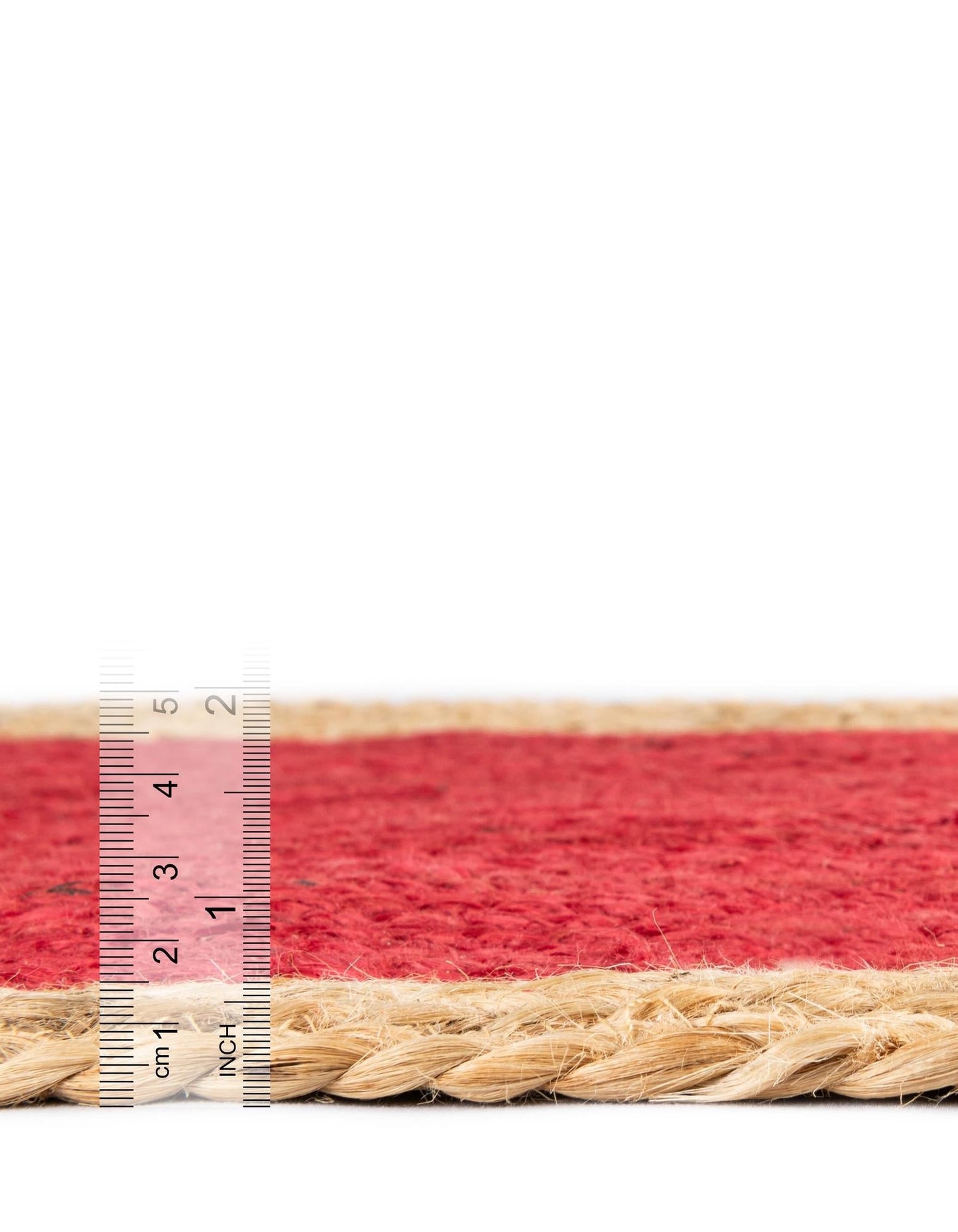 Close-up of a red and beige woven mat with a ruler for scale on a white background