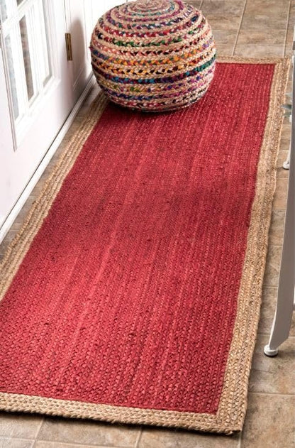 Red woven rug with a colorful ottoman on a wooden floor.
