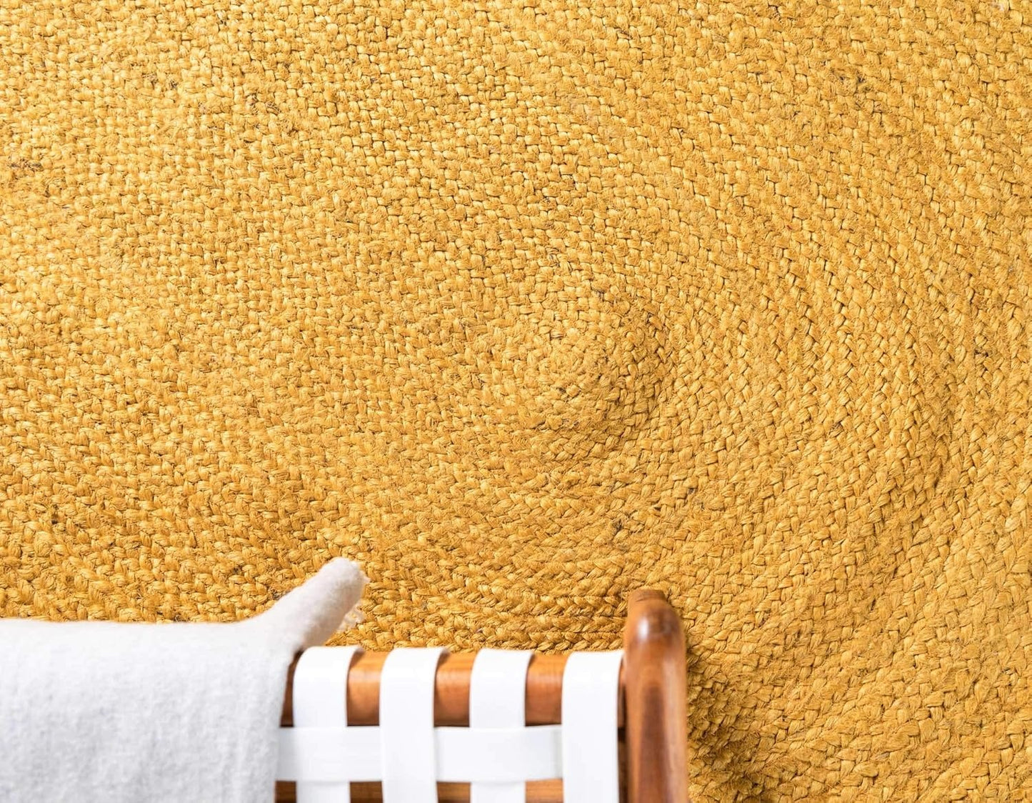 Close-up of a yellow carpet with a stain and a chair leg in the foreground.