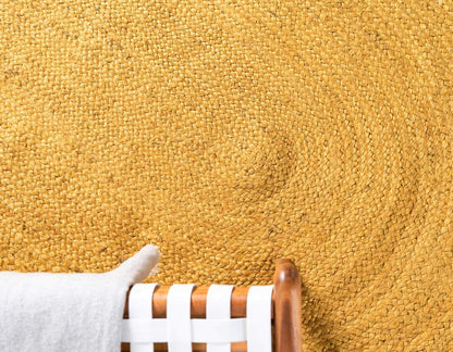 Close-up of a yellow carpet with a stain and a chair leg in the foreground.