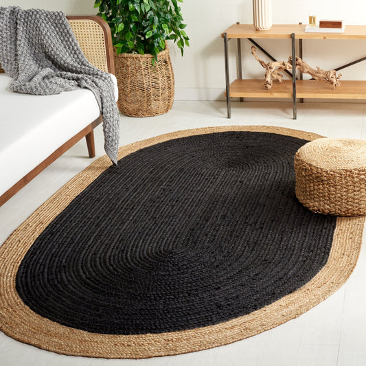Black and beige oval rug in a living room setting with a couch, plant, and side table.