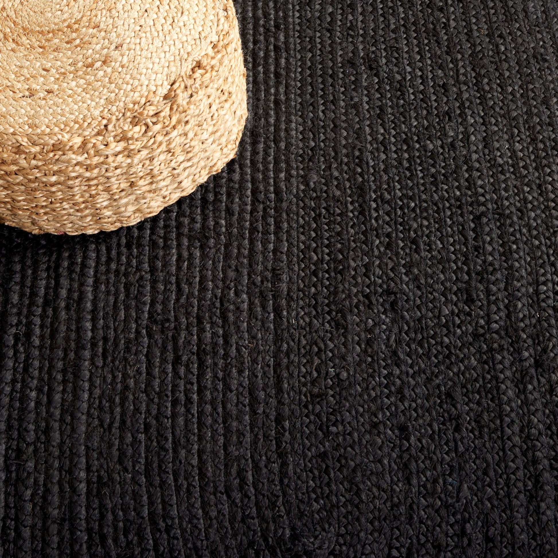 Close-up of a textured black rug with a woven beige object on top