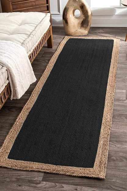 Black runner rug with natural border on wooden floor