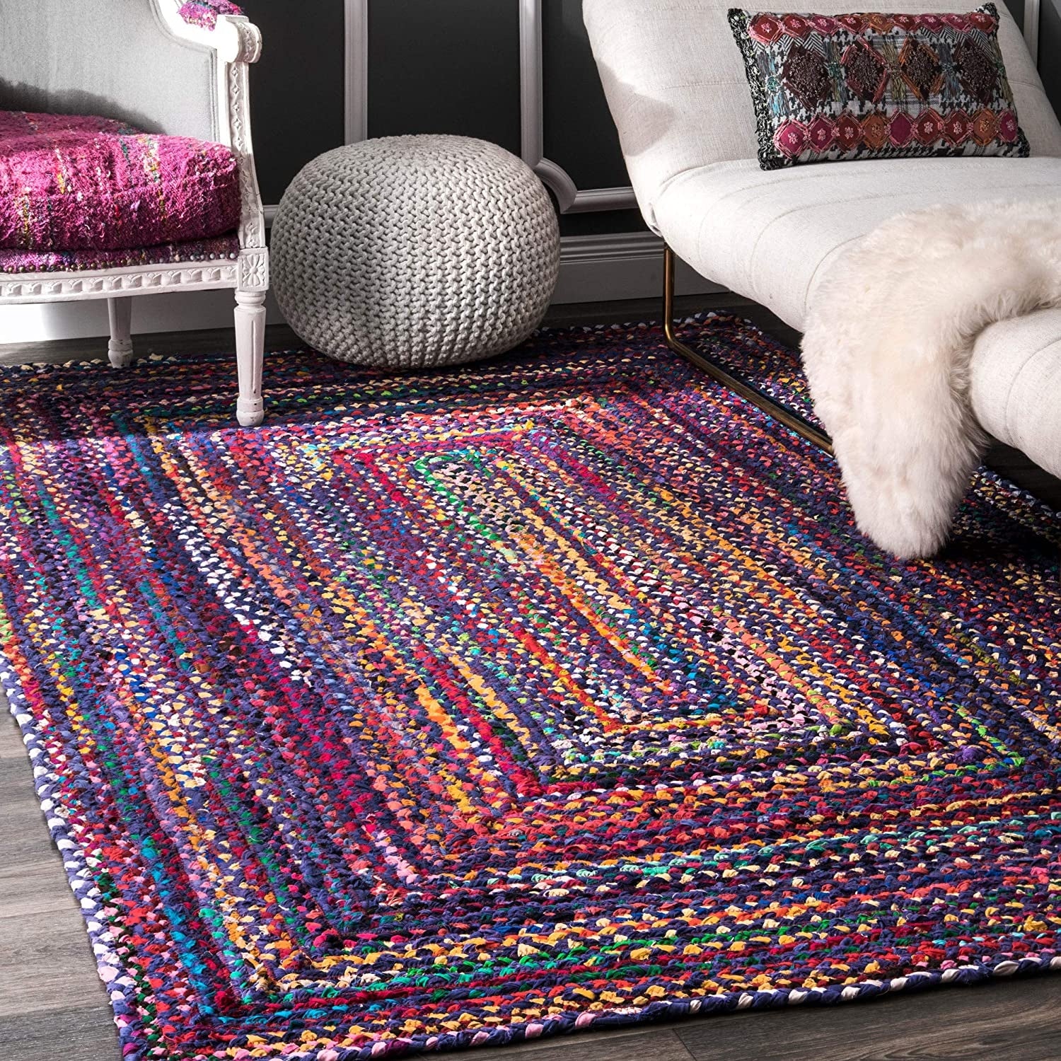 Multicolored braided rug in a room with a chair and ottoman.