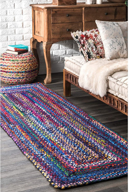 Colorful braided rug on a wooden floor with a wooden dresser and bench in the background.