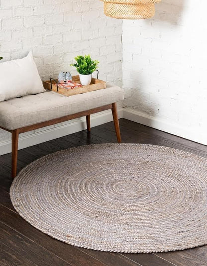 Round woven rug on a wooden floor with a bench and plant in the background.