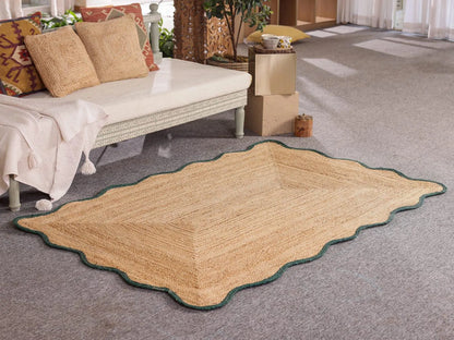 Beige area rug with scalloped edge on a gray carpeted floor.