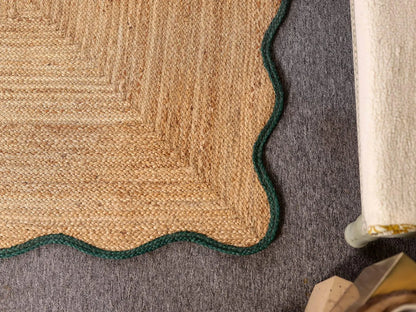 Close-up of a textured beige rug with a green border on a gray floor.